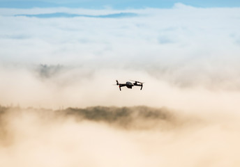 Fototapeta na wymiar The drone with cinema camera flying over the misty mountains at sunset