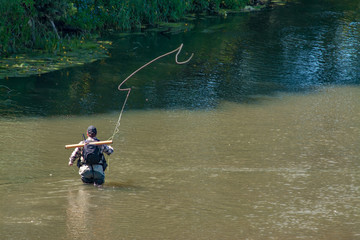 Obraz na płótnie Canvas The fisherman catches fish by fly fishing