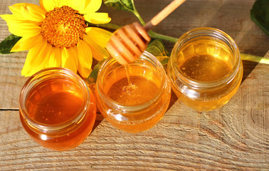 Honey in a glass jar with flowers on the wooden floor.