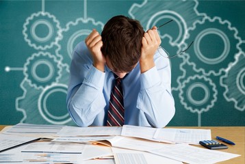 Tired young business man with a lot of  papers on the table