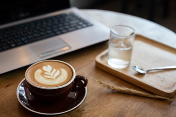 cup of coffee latte art on wood table in a cafe.