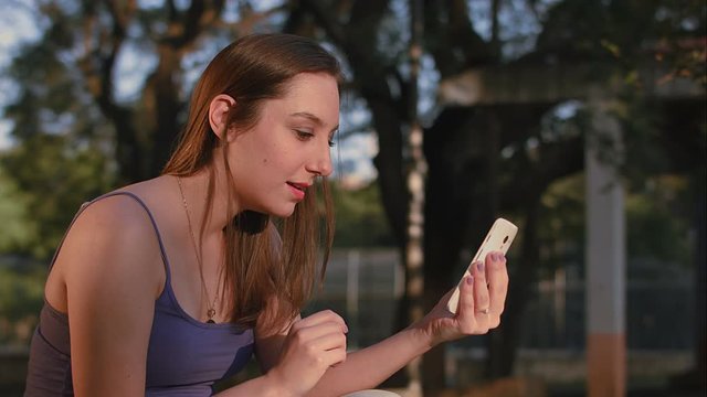 A brazilian woman using smartphone at park sunset in S&atilde;o Paulo