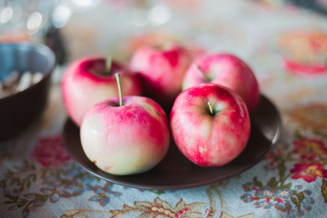 Five freshly picked red apples laying on the table on the brown plate
