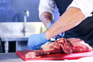 Butcher cutting pork meat on kitchen, Chef cutting fresh raw meat on board, Close up of butcher cutting meat