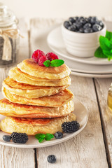 Pancakes with blueberries, honey and raspberry on a wooden background