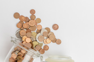 Fototapeta na wymiar Coins going out from a dropped glass jar, isolated on white