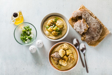 cream soup of cauliflower and potatoes in bowls on a table with fresh bread and green onions. healthy vegan cuisine.