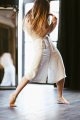 Sensual girl making dance movement near the window in backlit