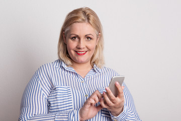Portrait of an attractive overweight woman with smartphone in a studio.