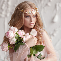Delicate portrait of a young model girl. The image of the bride, a light lace dress in pink, a beautiful hairstyle and a natural make-up. Light photo studio, natural light from the window.