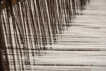 Brown and white threads in a weaving loom