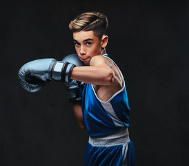 Fototapeta na wymiar Handsome young boxer during boxing exercises, focused on process with serious concentrated facial. Isolated on a dark background.