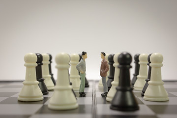 Closeup miniature businessman negotiate for cooperation on chess board with chess side view.