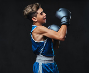 Fototapeta na wymiar Handsome young boxer during boxing exercises, focused on process with serious concentrated facial. Isolated on a dark background.