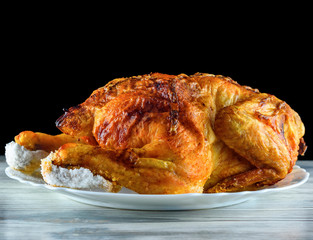 fried chicken whole, on a white plate on a wooden background