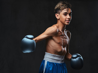 Handsome shirtless young boxer during boxing exercises, focused on process with serious concentrated facial.