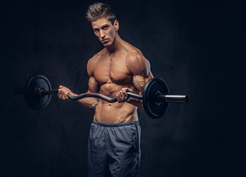 Handsome shirtless man with stylish hair and muscular ectomorph doing the exercises with the barbell.