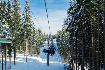 Fototapeta na wymiar Skiers and snowboarders on a ski lift.view from above on the cable car among the winter forest.