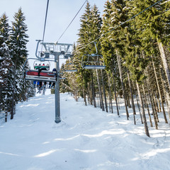Skiers and snowboarders on a ski lift.view from above on the cable car among the winter forest.
