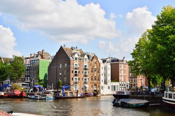 Amsterdamskie kamieniczki nad kanałem wśród zielonych drzew. © W Korczewski