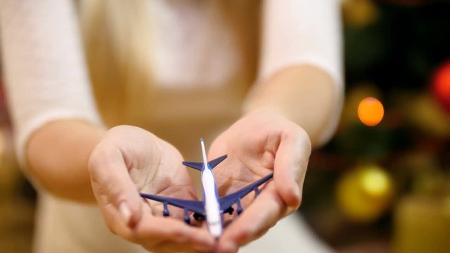 Closeup video of young woman holding small airplane in hands and showing it in camera. Concept of traveling on winter holidays