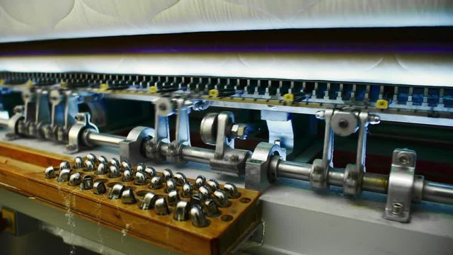 Close-up of computerized industrial quilting machine working with fabric at textile factory