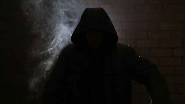 Maniac smokes nervously waiting for his victim in a dark alley