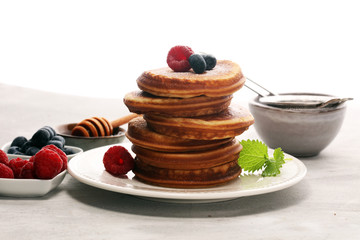 Pancakes with berries and maple syrup on rustic table