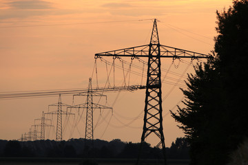 Fototapeta na wymiar Electricity pylons in the sunset photographed in Germany at the end of a hot summer day 