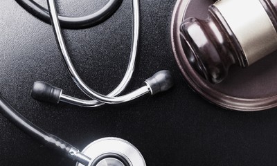 Gavel and stethoscope on wooden background, symbol photo for
