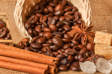 Coffee beans and cinnamon on a background of burlap. Roasted coffee beans background close up....