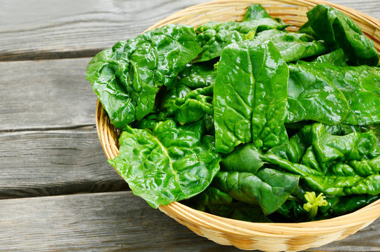 Benefits of Spinach leaves in basket on wooden floor.