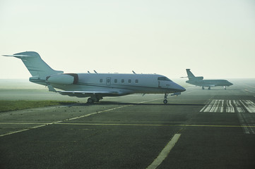 Jet planes parking at the airport. Small private airplanes at the airport parking in morning mist.