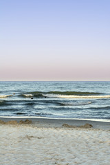 the sand beach and blue sea with waves and foam, sea sky at sunset time, nature abstract background