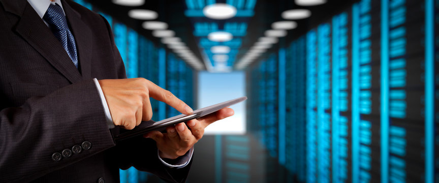 Businessman working with VR wide blank screen computer on server room in background.