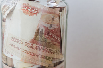 A large sum of Russian money in denominations of five thousand rubles is in a glass jar