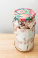 A large sum of Russian money in denominations of five thousand rubles is in a glass jar