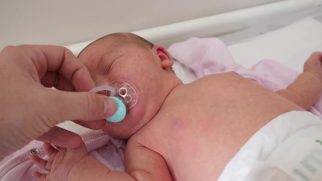 Giving a pacifier to crying newborn baby child in a maternity hospital