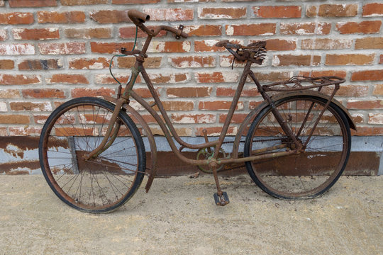 rusty bike in front of brick wall