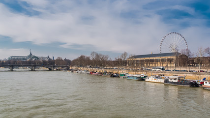 Paris, panorama of the Concorde bridge, the Grand-Palais in background, the big wheel and houseboats on the Seine 
