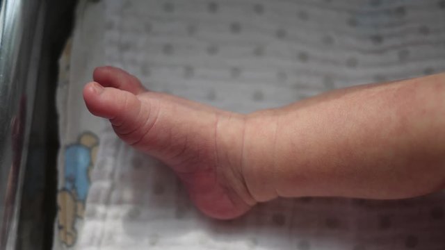Newborn baby little foot while child is sleeping in the maternity hospital bed