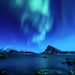 Fototapeta na wymiar Northern Lights, Aurora Borealis shining green in night starry sky at winter Lofoten Islands, Norway