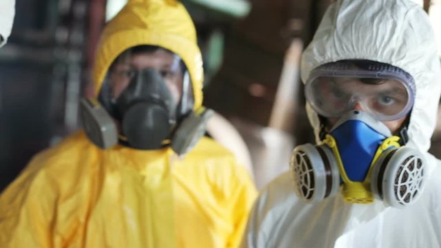 Eyes of two young Caucasian men wearing yellow and white hazmat suits. Serious guys looking attentively at camera. Indoors. Dangerous job. Close-up.