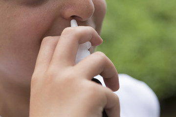 Close up shot of a child using nasal spray medicine for pollen allergy or upper respiratory tract diseases. 