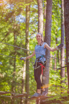 junges, blondes Mädchen klettert im Sommer im Kletterwald / Hochseilgarten 
