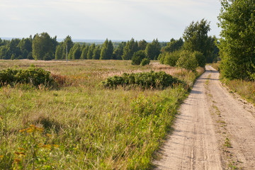 Dusty empty country road through a field