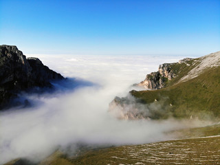 Mountain peaks of the Caucasus towering above the clouds. Fog in the mountain gorge.