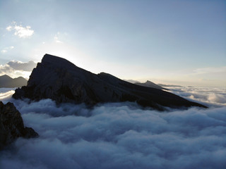 Mountain peaks of the Caucasus towering above the clouds. Fog in the mountain gorge.