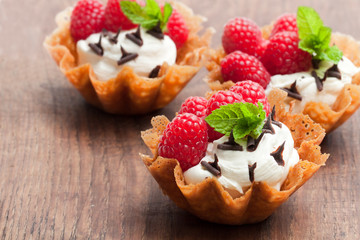 Brandy  snap baskets with ice cream and berries on wooden table