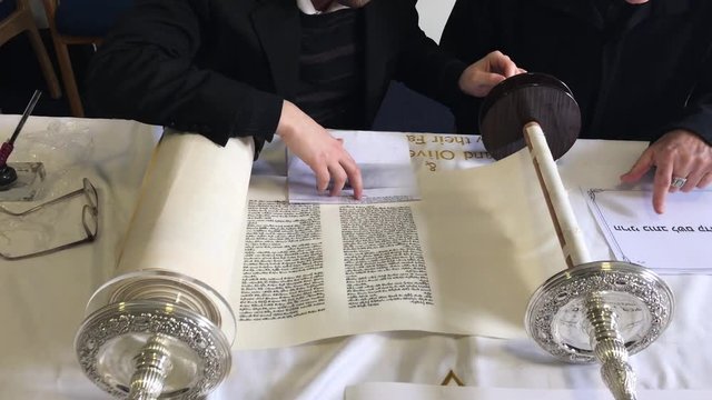 Jewish man holding Sofer hand while he writing a sefer Torah in Hebrew. In the Torah's 613 commandments, the second to last is that every Jew should write a Sefer Torah in their lifetime.
